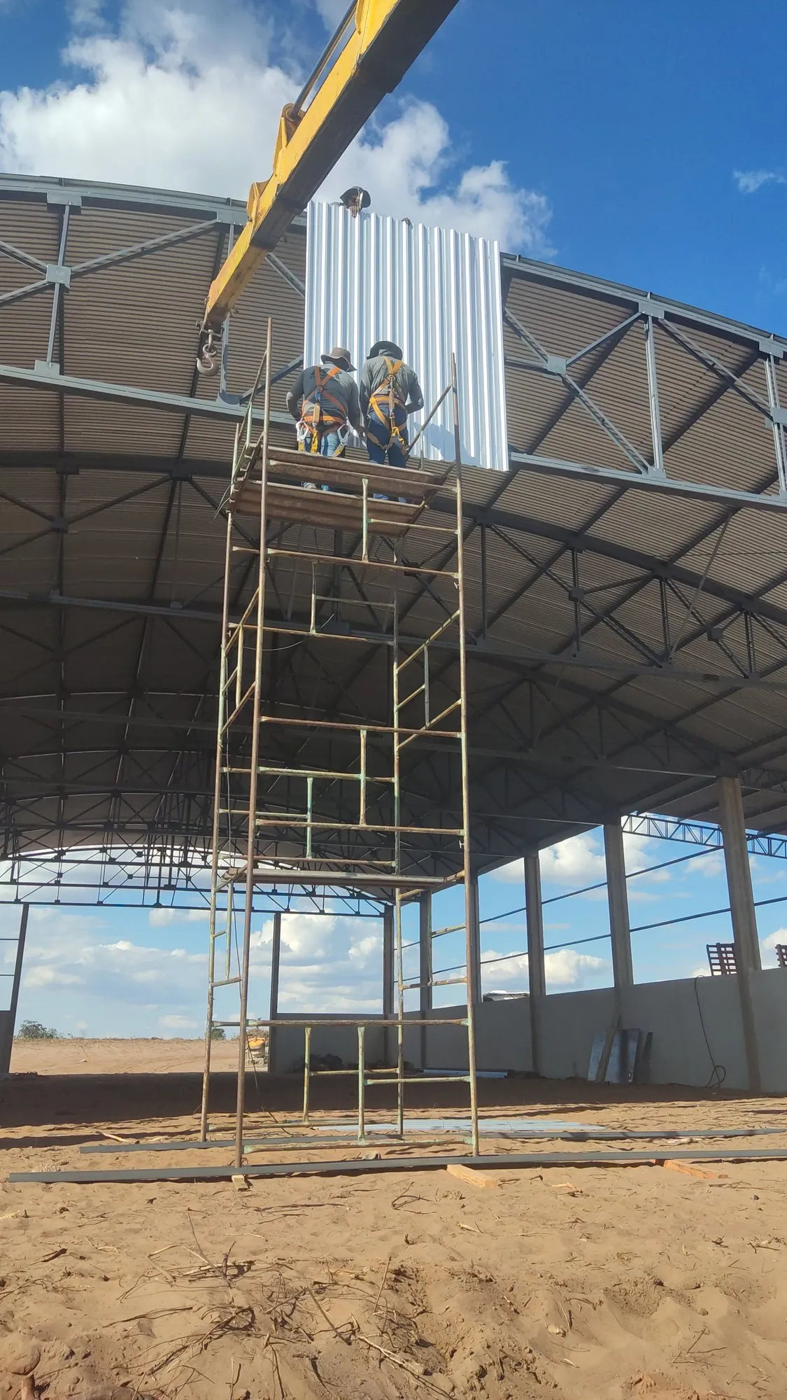 Equipe em andaime instalando fechamento de cobertura metálica de galpão — MR Serralheria