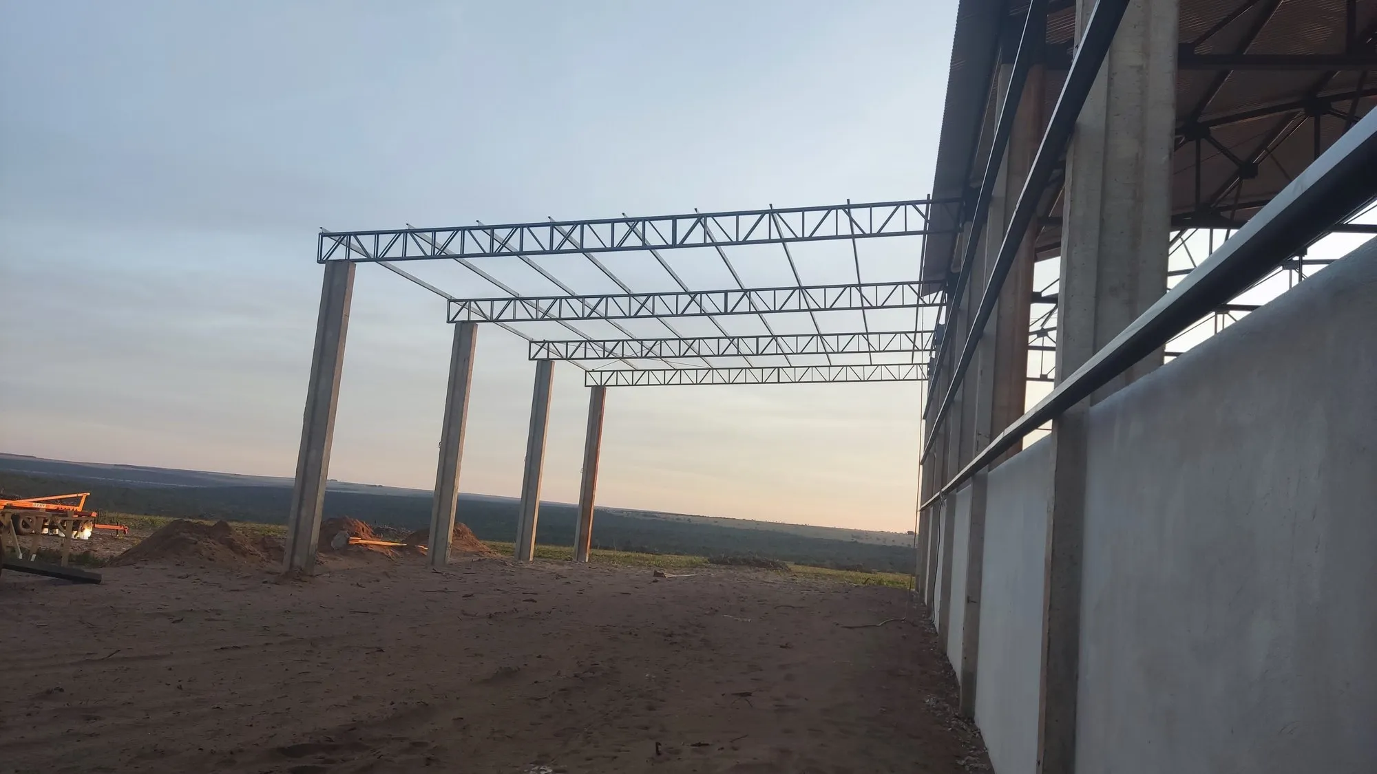 Vigas metálicas treliçadas apoiadas em colunas de concreto em obra rural — serralheria no Paraná